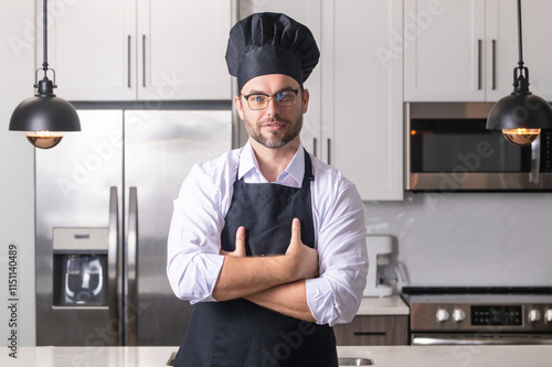 Handsome man chef in uniform cooking in the kitchen. Restaurant menu concept. Hispanic man in baker uniform. Cooking and culinary. Male chef in working uniform, black apron, chef hat. photo