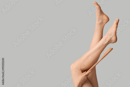 Legs of pretty young woman and brush on grey background photo