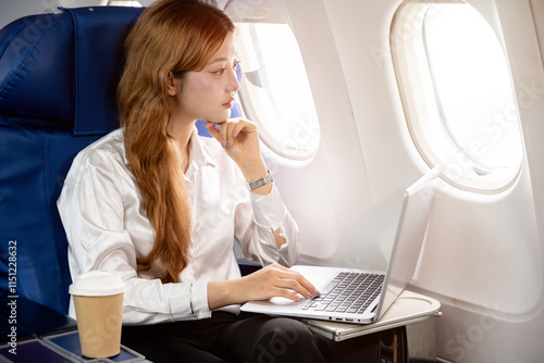 Asian businesswoman working on her laptop during a business trip flight.