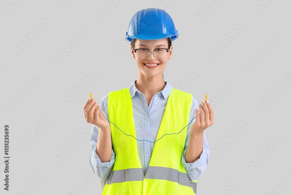 Female builder with earplugs on light background Female builder with earplugs on light background