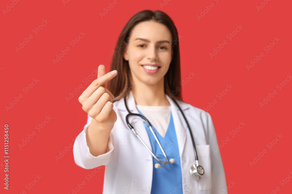Young female doctor making heart gesture on red background Young female doctor making heart gesture on red background