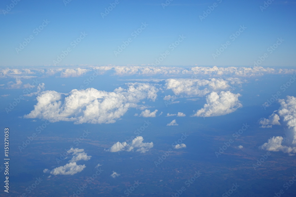 Fototapeta premium White clouds drift across the stratosphere against a blue sky. A few clouds dot the otherwise brilliant and pure sky. As if gazing up at a picturesque day, the scene is calm and tranquil.