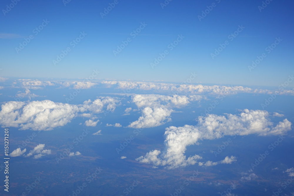 Fototapeta premium White clouds drift across the stratosphere against a blue sky. A few clouds dot the otherwise brilliant and pure sky. As if gazing up at a picturesque day, the scene is calm and tranquil.