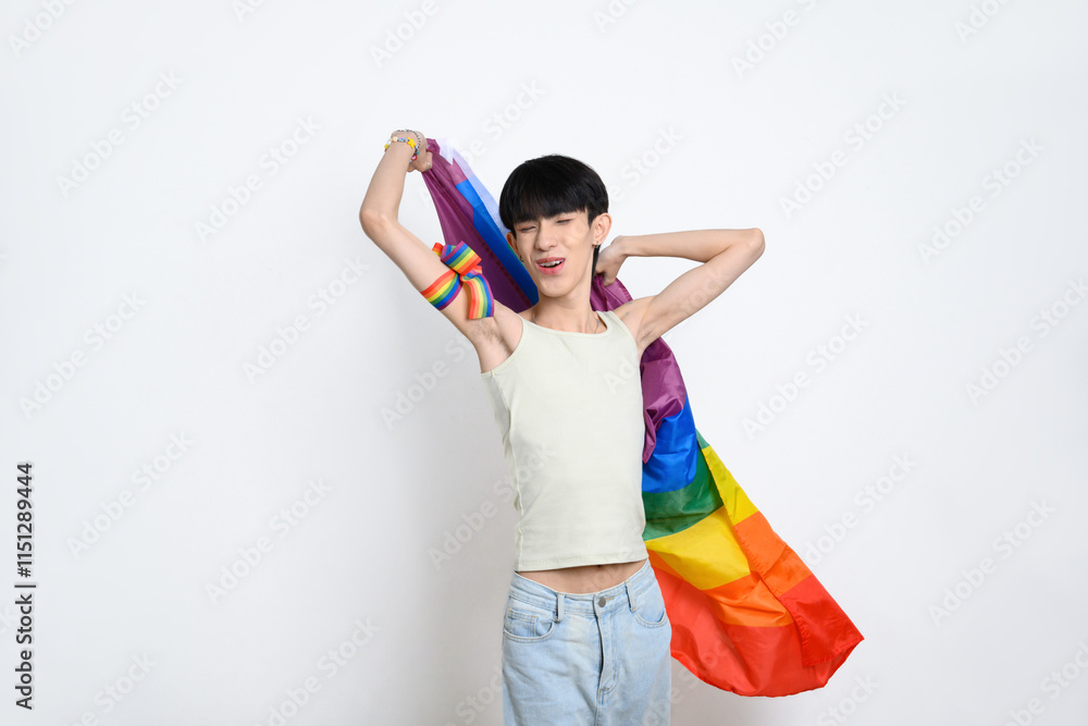Cheerful young gay man holding a rainbow pride flag on white background. LGBTQ pride and equality concept Cheerful young gay man holding a rainbow pride flag on white background. LGBTQ pride and equality concept