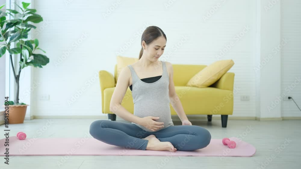 Pregnant Woman Sitting Cross-Legged on Yoga Mat in Living Room. Young Woman Embracing Relaxation, Mindfulness, and Prenatal Wellness. Young Pregnant Woman Peaceful and Comfortable. Pregnant Woman Sitting Cross-Legged on Yoga Mat in Living Room. Young Woman Embracing Relaxation, Mindfulness, and Prenatal Wellness. Young Pregnant Woman Peaceful and Comfortable.
