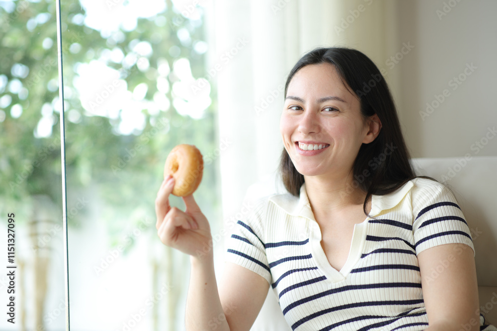 Happy asian woman posing holding doughnut at home Happy asian woman posing holding doughnut at home