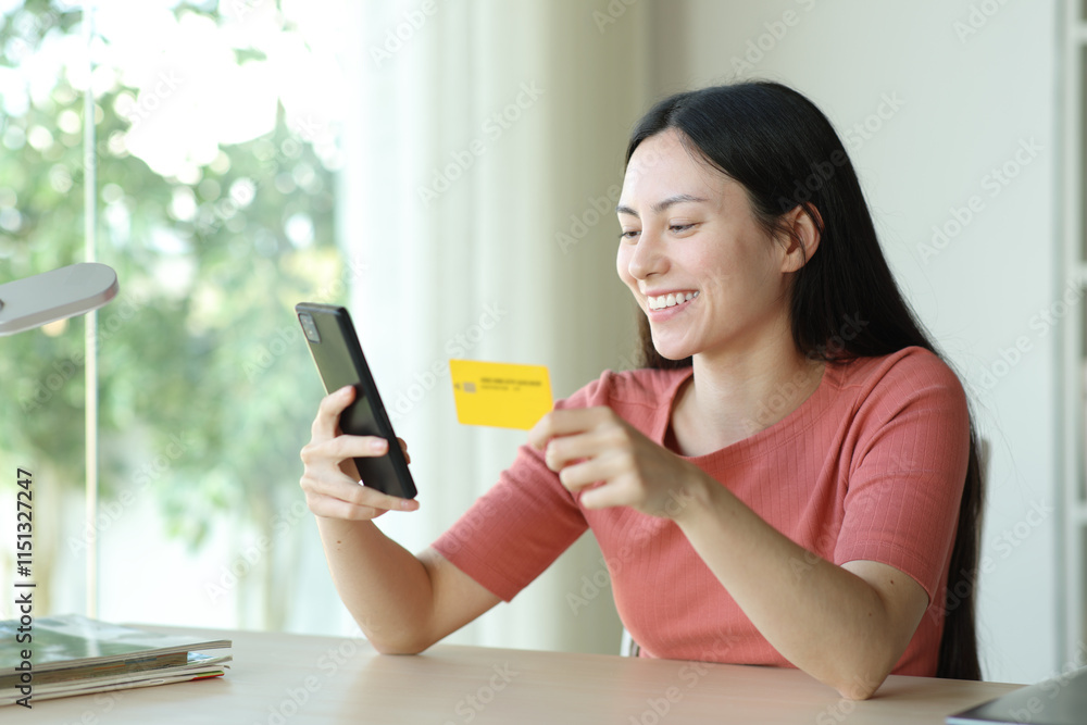 Happy asian woman buying online in a room Happy asian woman buying online in a room