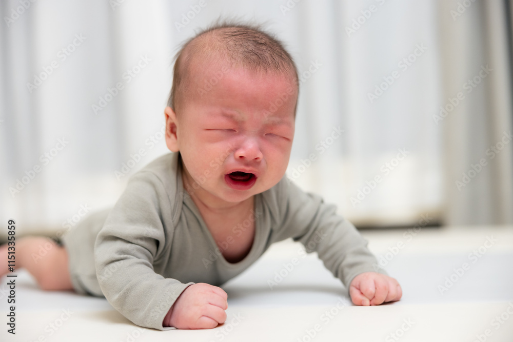 Upset baby crying on soft mat at home Upset baby crying on soft mat at home