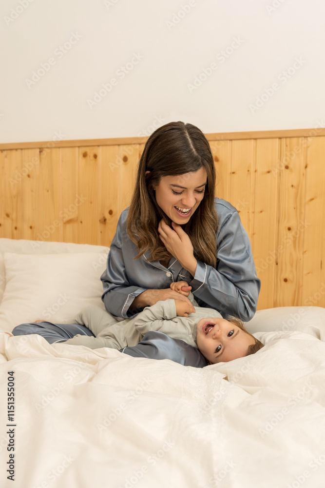 Relaxed family moment with laughter between a mother and her child in a warm bedroom Relaxed family moment with laughter between a mother and her child in a warm bedroom