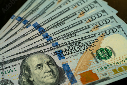 Stacks of hundred dollar bills arranged on a wooden surface photo