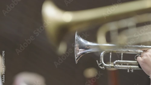 A person playing a solo on their silver plated trumpet in a professional symphony orchestra rehearsal sitting amongst other players. Nr.2