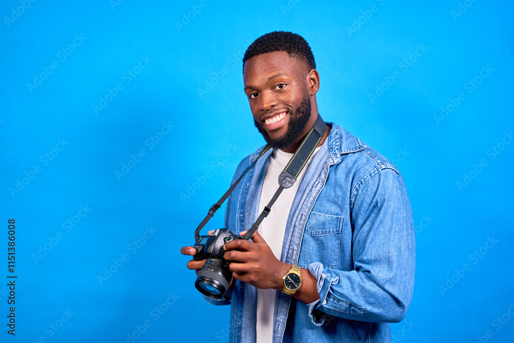 Photographer smiling and holding a dslr camera on blue background Photographer smiling and holding a dslr camera on blue background