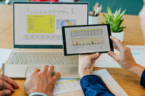 Colleagues comparing data on laptop and digital PC in office
