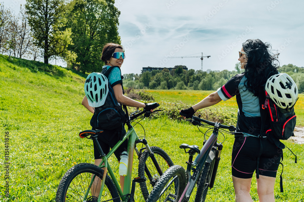 Happy friends with cycles at meadow on sunny day Happy friends with cycles at meadow on sunny day