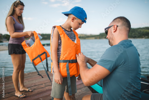 Father helping his son put on a life jacket before kayaking photo