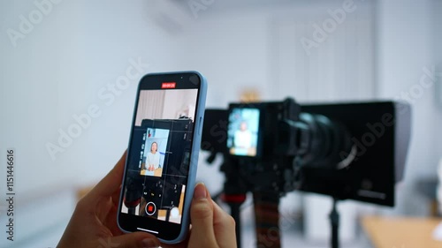 Recording display of a professional camera to a smartphone. Lady is taking video on her phone. Close up.