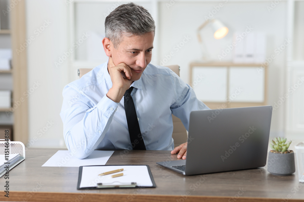 Businessman working with laptop at table in office Businessman working with laptop at table in office