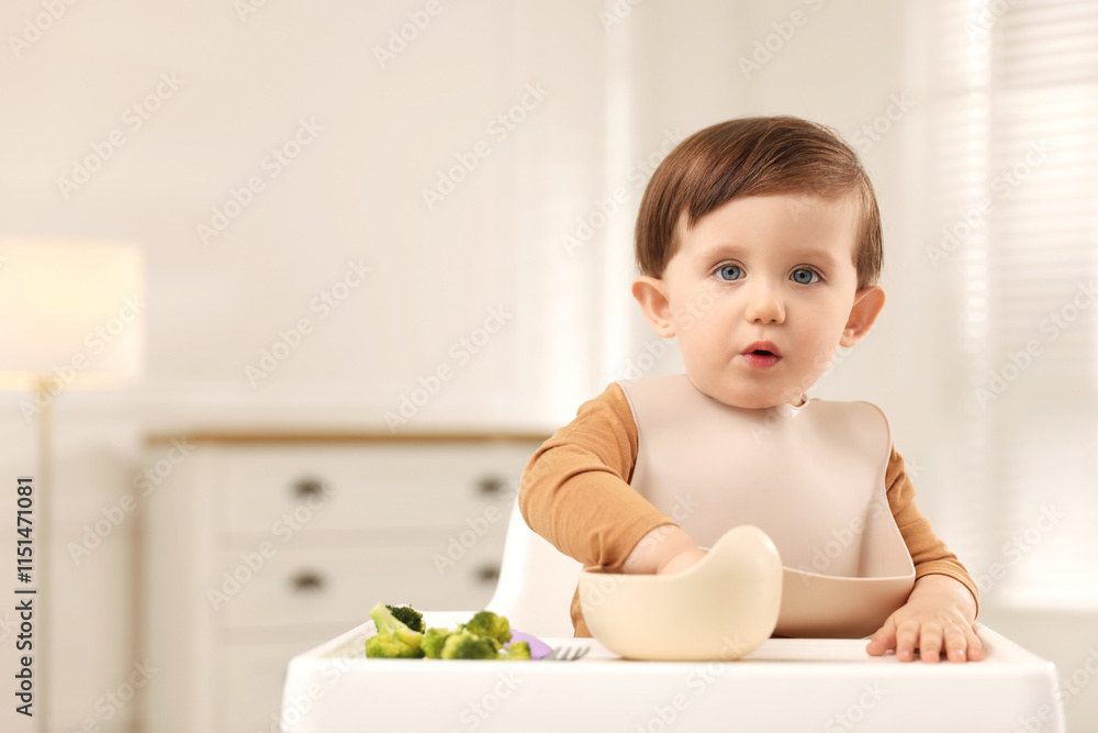 Cute little baby eating healthy food from bowl in high chair at home, space for text Cute little baby eating healthy food from bowl in high chair at home, space for text