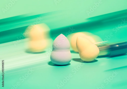 Vibrant blurred motion of makeup sponges on mint green background photo