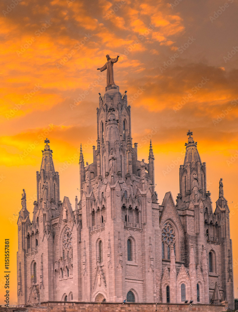 Fototapeta premium Expiatory Church of the Sacred Heart of Jesus, located on Mount Tibidabo in Barcelona, set against a dramatic orange sunset.