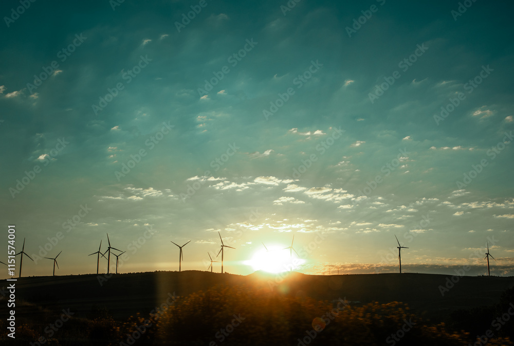 Fototapeta premium The sun rises over the horizon in the morning Wind turbines with propellers on horizon Energy generator on wind farm against blue sky Renewable energy