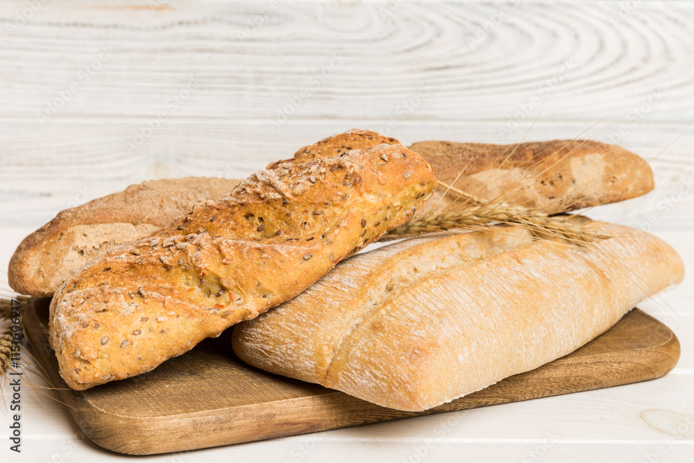 Freshly baked bread on cutting board against white wooden background. perspective view bread with copy space Freshly baked bread on cutting board against white wooden background. perspective view bread with copy space
