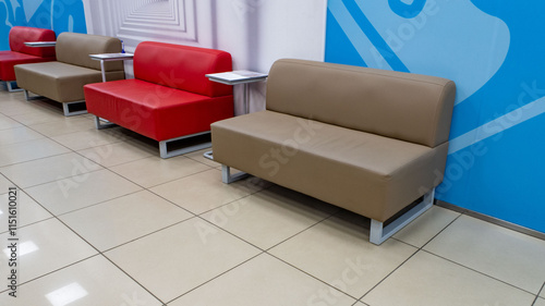 A row of couches are lined up in a room with a blue wall behind them photo