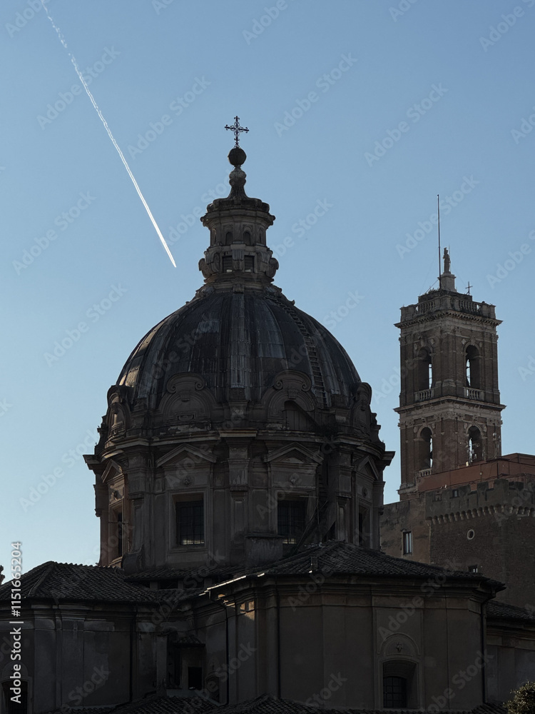 Historic dome and bell tower under a clear sky with contrails contrasting the ancient architecture at sunset in a European city Historic dome and bell tower under a clear sky with contrails contrasting the ancient architecture at sunset in a European city