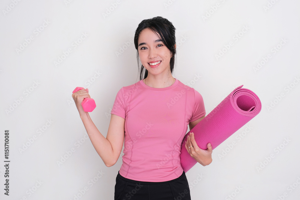 A woman wearing sportswear smiling happy while holding a dumbbell and yoga mat A woman wearing sportswear smiling happy while holding a dumbbell and yoga mat