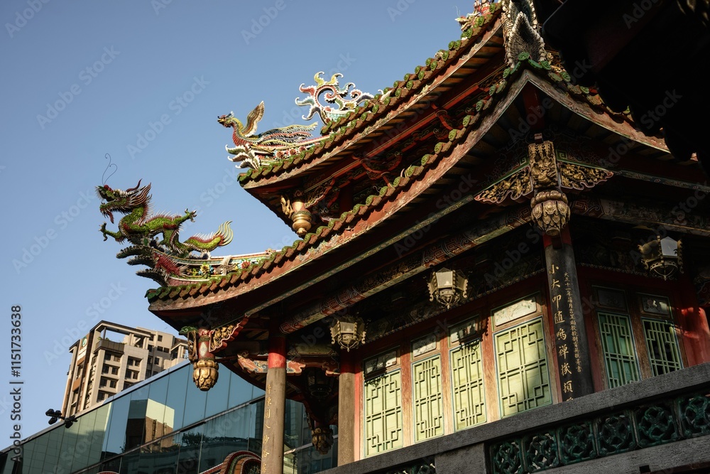 Fototapeta premium Traditional Chinese temple roof with ornate dragon carvings under a clear blue sky.