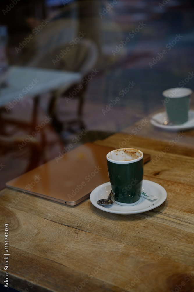 coffee and laptop on wooden table through the glass