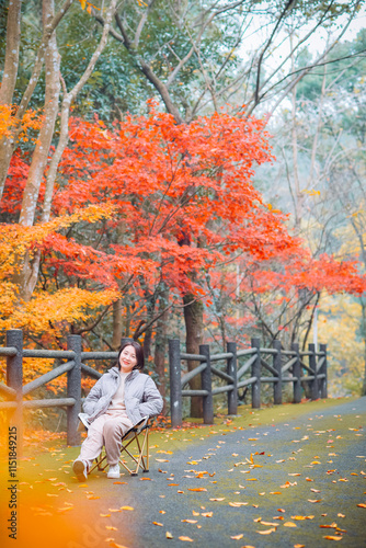 One Asian woman enjoying beautiful autumn foliage scenery of vibrant maple trees during December at Dujuan Valley in Xikou, Fenghua, Ningbo, Zhejiang, China photo