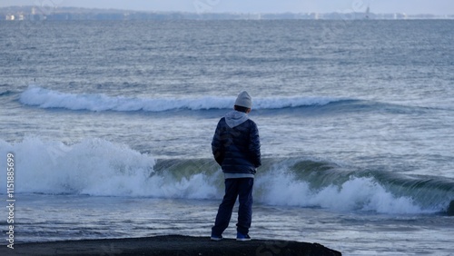 Canvas Print This poignant photograph captures a solitary boy standing by the shore, gazing out at the vast, open sea