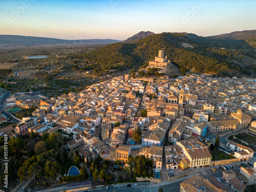 Cinematic aerial view of Biar city, at sunset. Beautiful medieval city. Fortress on top of the hill. Warm sunset colours reflecting on the landscape and castle. Famous travel destination in Spain. photo