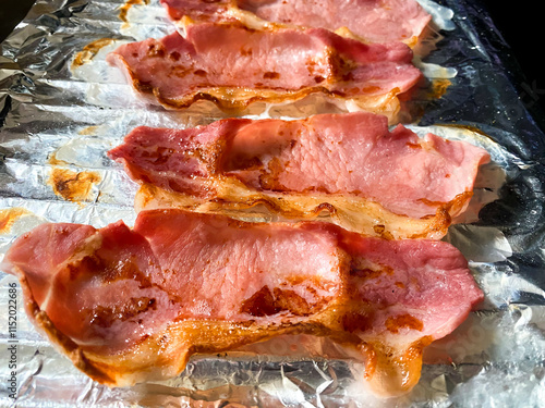 Grilled bacon rashers on a grill pan covered in aluminium foil