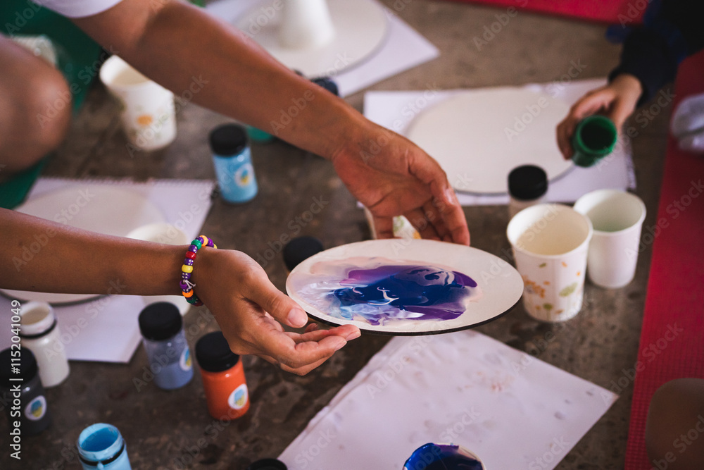 Obraz premium Fluid art. Master class for children on drawing. Art therapy. Drawing with acrylic paint on a round canvas. A group of children develops creatively.
