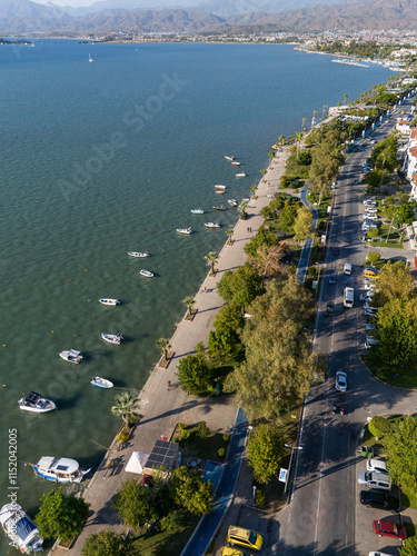 A bicycle path through the trees. The coastal path that runs right next to the sea. Parked boats. Buildings built next to the coastal path. Shadows of trees and boats from the evening sun coming from.