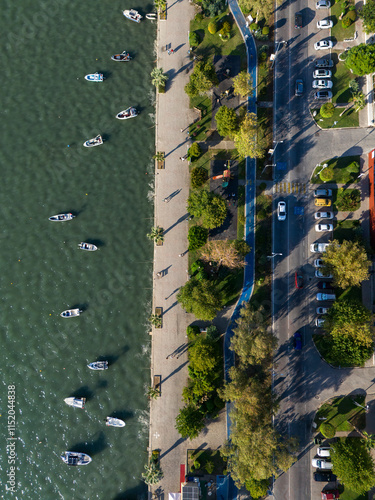 A bicycle path through the trees. The coastal path that runs right next to the sea. Parked boats. Buildings built next to the coastal path. Shadows of trees and boats from the evening sun coming from.