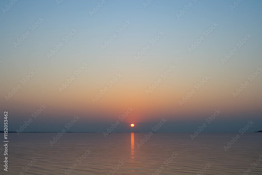 Fototapeta premium Scenic Gradient Sunset Sky: Deep Orange to Light Blue with Calm Water Reflection and a Clear Horizon