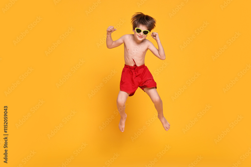 Little boy in beachwear jumping on orange background, space for text Little boy in beachwear jumping on orange background, space for text