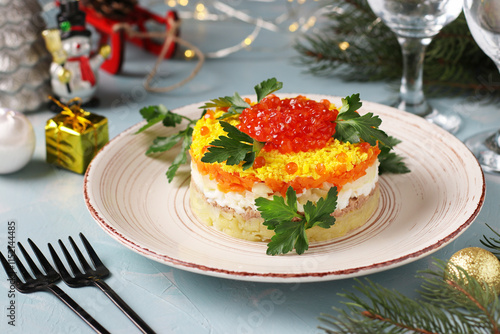 Festive salad Mimosa with canned fish, potatoes, cheese, carrots and eggs, garnished with red caviar and parsley leaves photo