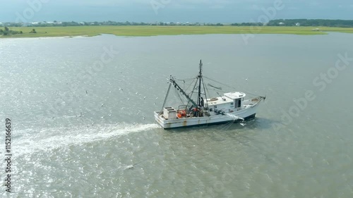 Aerial circling shot of a shrimp boat pulling nets off the coast of Harbour Island, South Carolina near Beaufort.