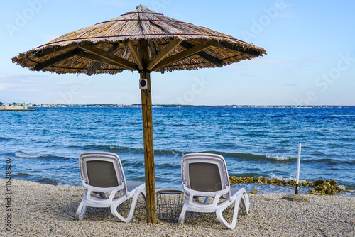 Fototapeta Naklejka Na Ścianę i Meble -  Empty beach cafe without visitors after the end of the season, reed sunshades, empty sunbeds