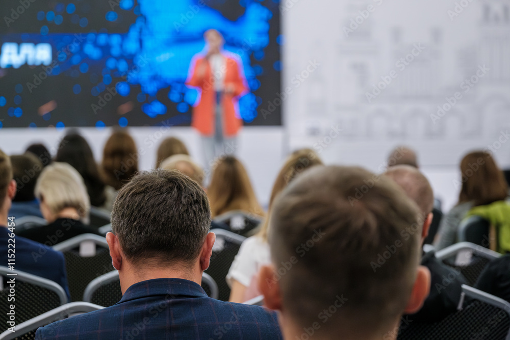 Obraz premium People attending a conference, focused on a presentation by speaker on stage. Audience engaged and seated in modern business event. Capturing professional environment collective gathering discussion