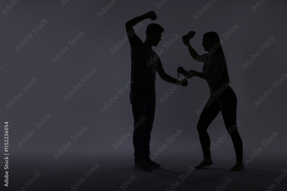 Domestic violence. Silhouette of man threatening his wife on grey background Domestic violence. Silhouette of man threatening his wife on grey background
