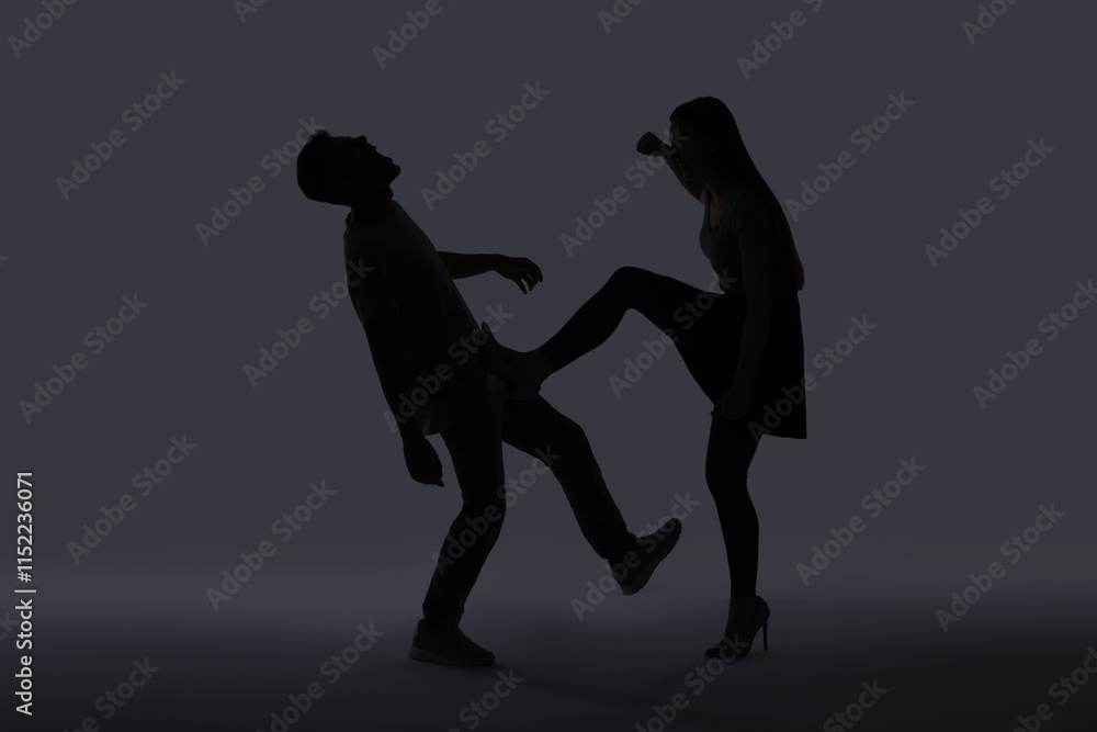 Domestic violence. Silhouette of woman kicking her husband on grey background Domestic violence. Silhouette of woman kicking her husband on grey background