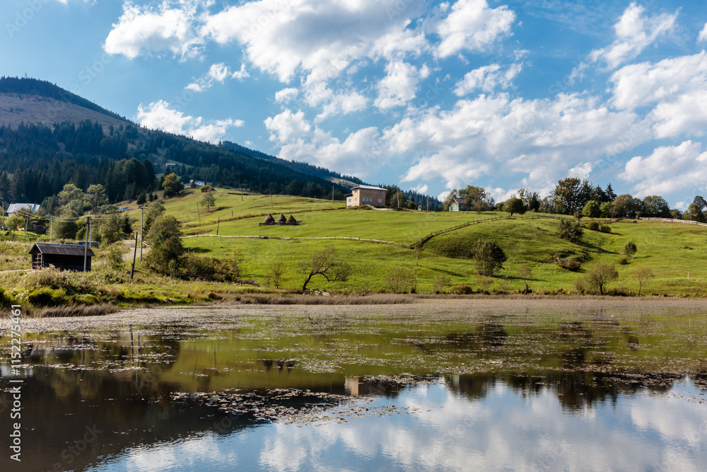 A peaceful countryside scene with a lake and a house in the distance A peaceful countryside scene with a lake and a house in the distance