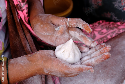 Woman making sweet rice modak stuffed with grated coconut and jaggery, Steamed or ukdiche Modak. It's a traditional sweet dish made out of coconut, jaggery photo