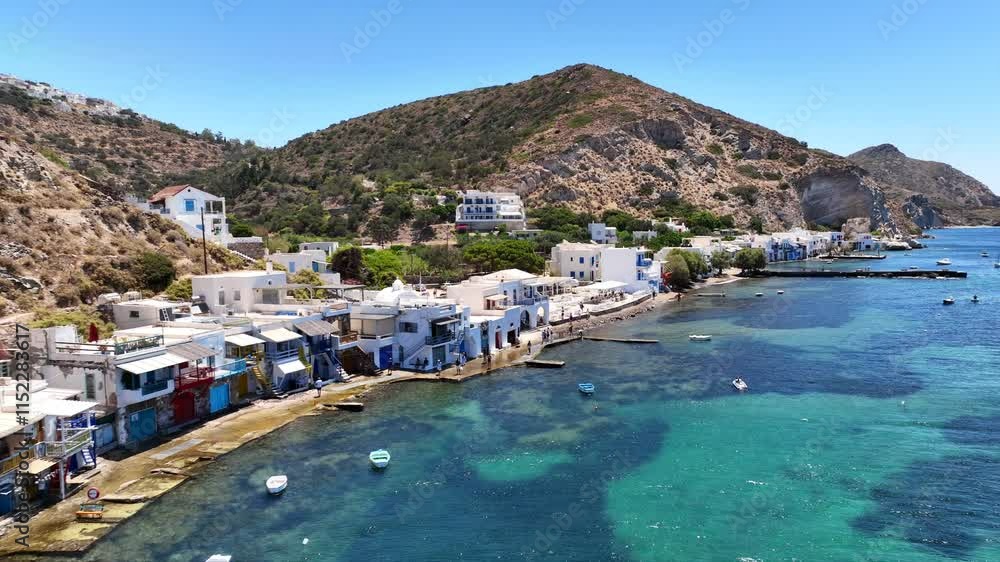 Aerial drone cinematic video of iconic and picturesque fishing village of Klima built by the shore with colourful traditional fishing boat houses called syrmata in island of Milos, Cyclades, Greece