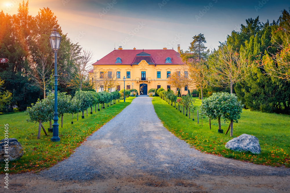 Naklejka premium Empty walkway to the ancient Eckartsa castle. Impressive autumn cityscape of Eckartsau village, in the district of Ganserndorf, Austria, Europe. Fantastic sunset in Austrian countryside.